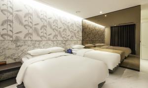 仁川市Incheon Guwol Hotel Bay 204的一间卧室设有三张床,墙上有鲜花