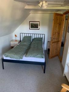 赫尔辛厄Dyrlundgaard tilbyder charmerende ferielejlighed.的一间卧室配有一张带绿色床单的床和木门。