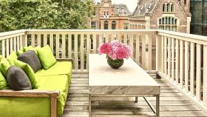 阿姆斯特丹Conservatorium Hotel的阳台的长沙发和桌子,花瓶
