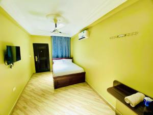 库马西Abanaba lodge& Restaurant的一间黄色的小房间,配有床和电视
