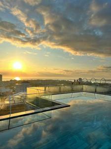 绥和市PHÚ YÊN EVERYDAY HOTEL的一座享有日落美景的建筑屋顶上的游泳池