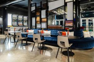阿林顿Aloft Dallas Arlington South的一间带桌椅和蓝色沙发的餐厅