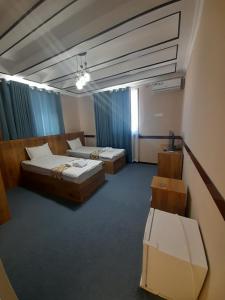 布哈拉Hotel Al Hayit Teracce的配有蓝色窗帘的客房内的两张床
