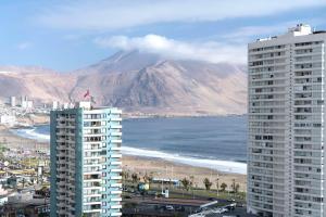 伊基克NH Iquique Pacifico的享有山脉、海滩和两栋建筑的景致