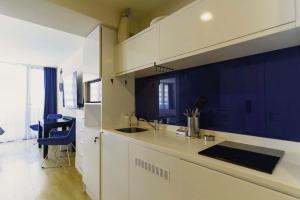 巴统Elegance Sea View Aparthotel In Orbi City Batumi的厨房配有白色橱柜和蓝色的墙壁