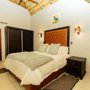 雾观Kruger Park Lodge Unit 531 - PMP的一间卧室配有一张大床和木制床头板