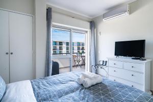 阿玛考德佩拉Beachfront apartment in Armação的一间卧室配有一张床、一台电视和一个阳台