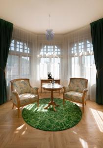 卡罗维发利安巴萨多纳罗迪德酒店的客厅配有两把椅子和一张桌子