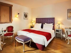 斯特拉斯堡Hotel Cour du Corbeau Strasbourg - MGallery的酒店客房带一张大床和椅子