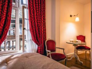 斯特拉斯堡Hotel Cour du Corbeau Strasbourg - MGallery的一间卧室配有一张床、一张桌子和一个窗户。