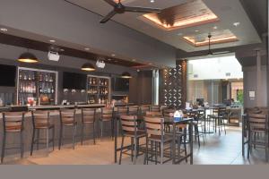 奥拉西Embassy Suites by Hilton Kansas City Olathe的一间带桌椅的餐厅和一间酒吧