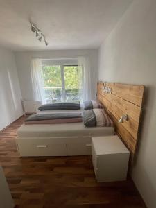 WasserhofenFEWO CELINE的一间卧室配有一张带木制床头板的床和窗户。