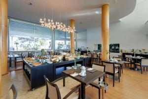 莱萨·达·帕尔梅拉TRYP by Wyndham Porto Expo Hotel的一间带桌椅和吊灯的餐厅