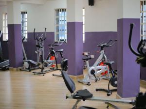 库马西Abanaba lodge& Restaurant的紫色墙壁的健身房里的一排健身自行车