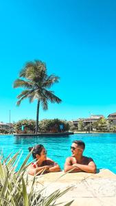 阿奎拉兹Golf Ville Resort Brisa do Golf -Apartamentos e Cobertura的两个人躺在游泳池里