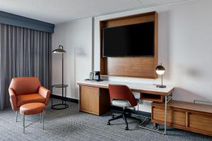 底特律Courtyard by Marriott Detroit Downtown的酒店客房配有书桌、电视和椅子。