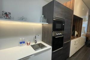 麦纳麦Cloud9 Waterfront Luxury Condo的厨房配有水槽和黑微波炉