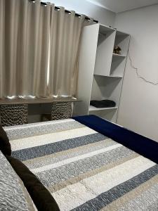 莫索罗Studio no West Fit Mossoró Alto Padrão的一间卧室配有一张带蓝色棉被和窗帘的床