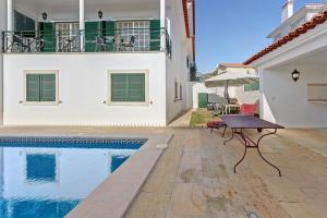 卡斯卡伊斯Mansão Domiga Adão的房屋旁设有游泳池和桌子的房子
