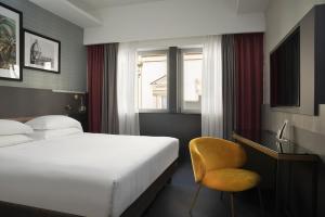 佛罗伦萨iQ Hotel Firenze的酒店客房,配有床和黄色椅子