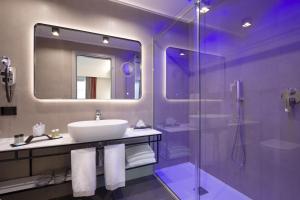 佛罗伦萨iQ Hotel Firenze的一间带水槽和玻璃淋浴的浴室
