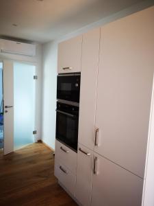 格拉茨Cosy Apartment next to the center of Graz的厨房配有白色橱柜和黑烤箱。