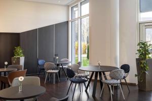 奥伯丁NH酒店慕尼黑机场店的餐厅设有桌椅和窗户。