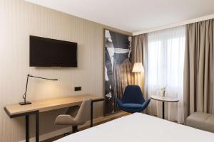 奥伯丁NH酒店慕尼黑机场店的一间酒店客房,配有一张床和一台墙上的电视