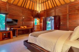 苏卡瓦提Sri Abi Ratu Villas的木制客房内的一间卧室,配有一张床
