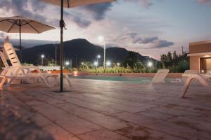 拉里奥哈Casa Adela - Cabañas Resort的一个带椅子和遮阳伞的庭院和一个游泳池