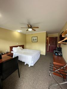 WaasisTravellers Inn Fredericton NB的卧室配有白色的床和吊扇