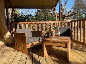 阿维尼翁Lodges & Nature - 49的木甲板上配有桌子和一杯葡萄酒