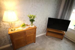 阿兴顿Ashington - 2 Bedroom House - Beautifully Decorated & Furnished - Large Garden的客厅配有电视和梳妆台灯