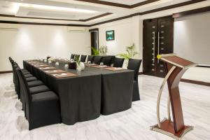 欧丘里欧Sago Palm Hotel的一间会议室,配有长桌子和黑椅子