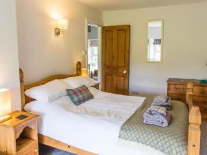 布莱奈费斯蒂尼奥格Moelwyn View Cottage的卧室配有白色的床和木制橱柜。
