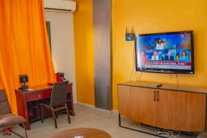 黑角Mayombe Arena Hotel的一间起居室,在黄色的墙上配有电视