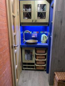 尼古拉耶夫Студія з внутрішнім півповерхом.的小厨房设有水槽和蓝色的墙壁