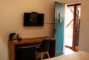 塞古罗港Suites da Loja Caraíva的一间设有一张桌子和一台墙上的电视的房间