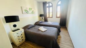 奎特里拉Charming triplex T2 in the Old Village Vilamoura的一间卧室设有两张床、一个梳妆台和窗户。