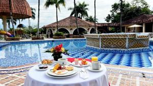 比亚维森西奥Tequendama Hotel Campestre Villavicencio的游泳池旁的餐桌上放着食物