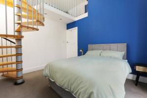 Nether EdgeSemi-Detached House Featuring a Mezzanine Level的一间卧室设有蓝色的墙壁和一张带楼梯的床。