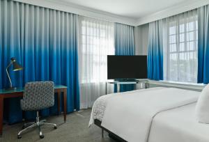 达拉斯达拉斯斯通雷利艾美酒店的一间卧室配有一张床、一张书桌和一台电视。