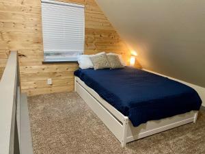 阿什福德NEW Modern Cabin! 5mi to Mt Rainier National Park! Hot Tub & Wifi的卧室配有一张床铺,位于带木墙的房间内