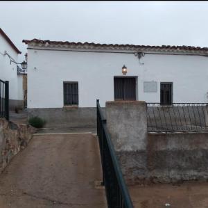 塞维利亚La casita en la Alcornocosa -Sevilla的前面有栅栏的白色建筑