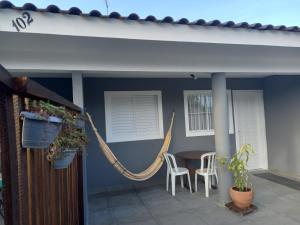 马蒂尼奥斯Casa 50 mts da praia Caravelas PR com ventiladores的门廊配有吊床和桌椅