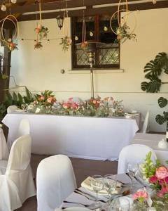 利马切Hotel Fundo Las Tortolas的用餐室配有带白色椅子和鲜花的桌子