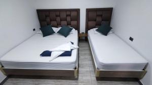 麦德林Hostel Boutique Nido de Loros的两张带白色床单和蓝色枕头的床