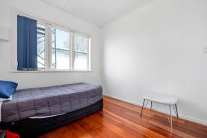 罗托鲁瓦Lakeview Small Studio的一间卧室配有一张床、一个凳子和一扇窗户