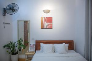河内Hanoi All Nations Homestay的一间卧室配有一张带白色床单的床和风扇