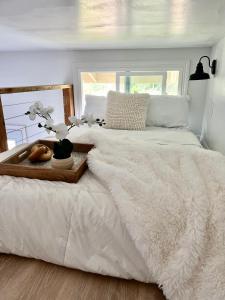 凯阿奥Hale ‘Aina (Country Cottage)的一张白色的床,上面有鲜花的木制托盘